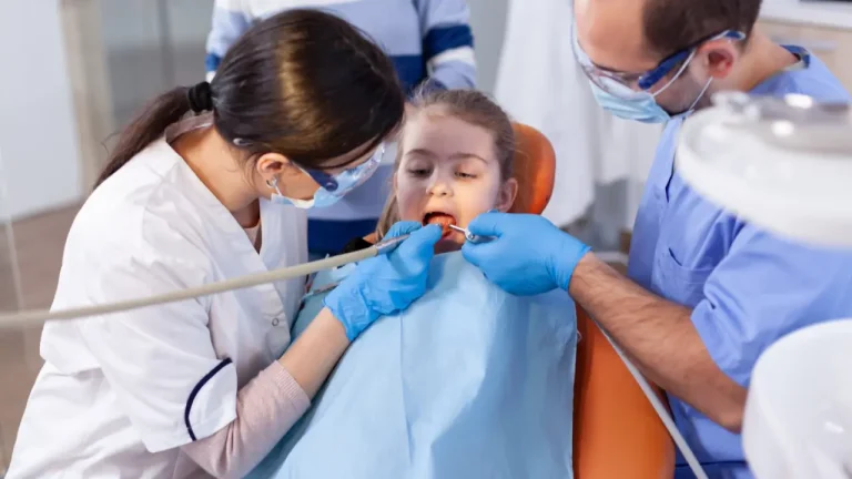 Dentists cleaning young child teeth in clinic chair