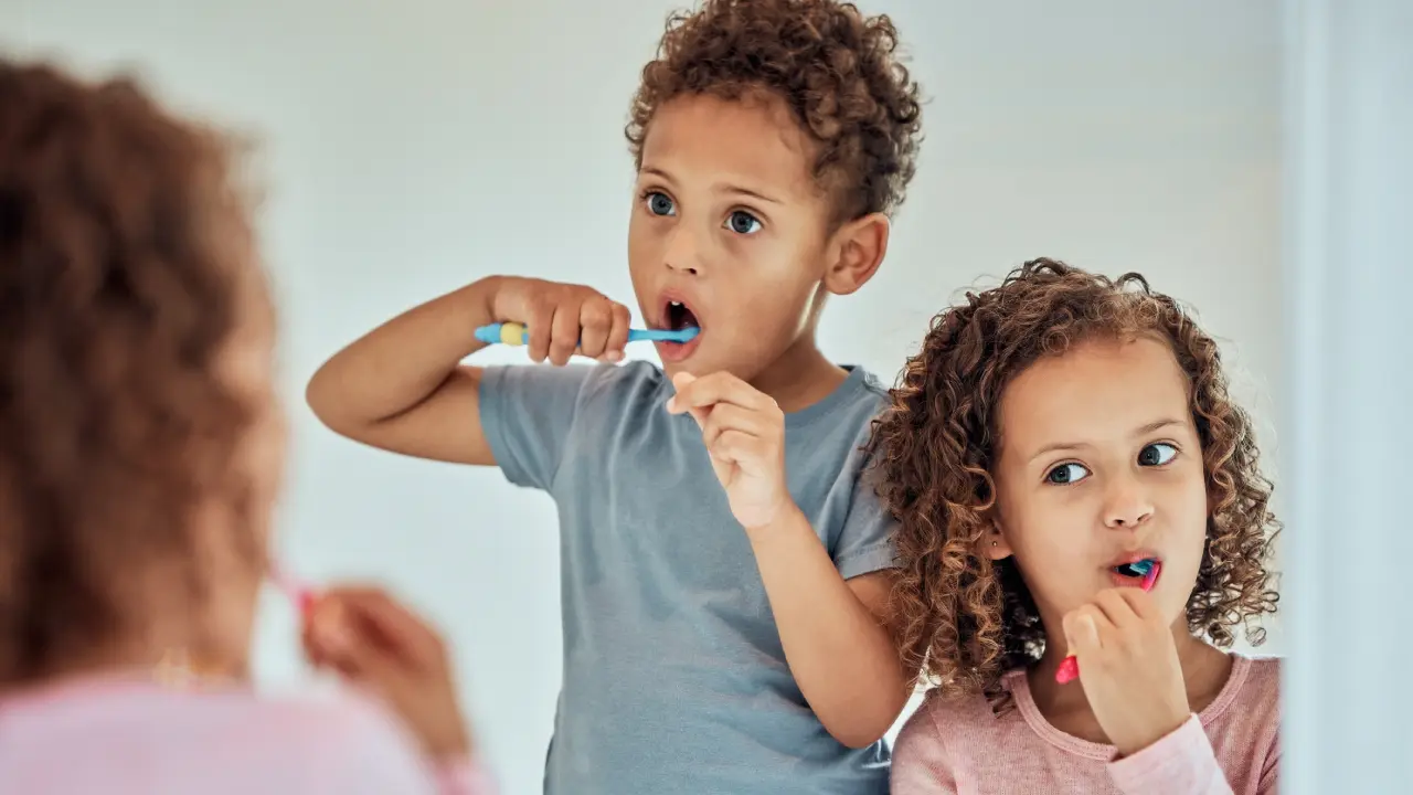 Children brush teeth in bathroom with mother