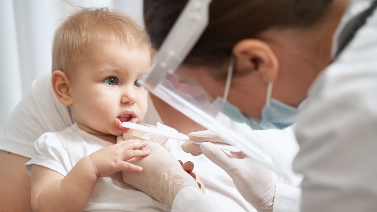Infant receiving early dental checkup with parent nearby