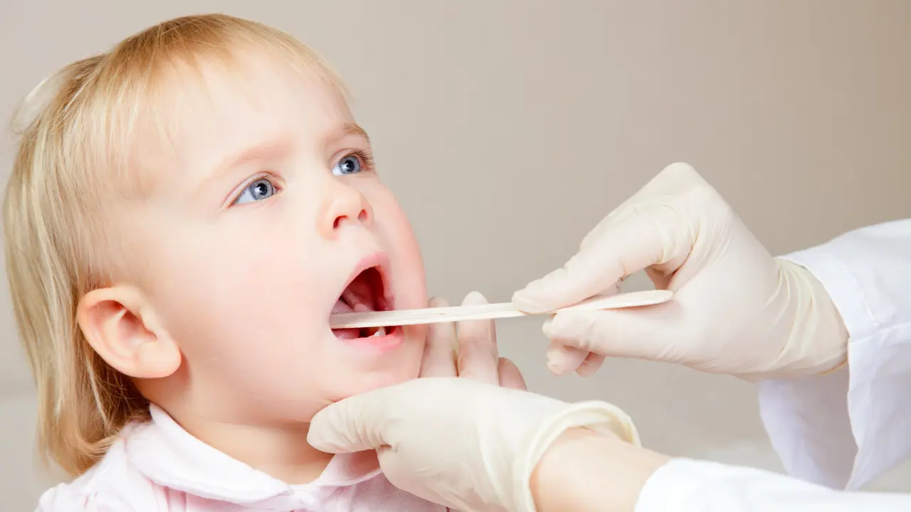 Pediatric dentist examining a child's mouth to evaluate for a possible frenectomy