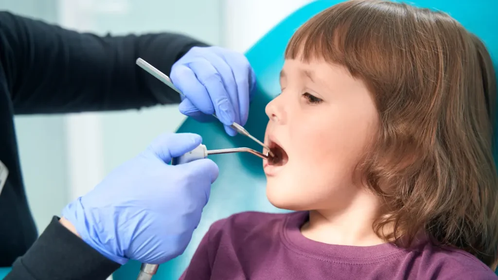 Pediatric dentist examining a child's tooth before deciding if tooth extraction is needed in Dubai