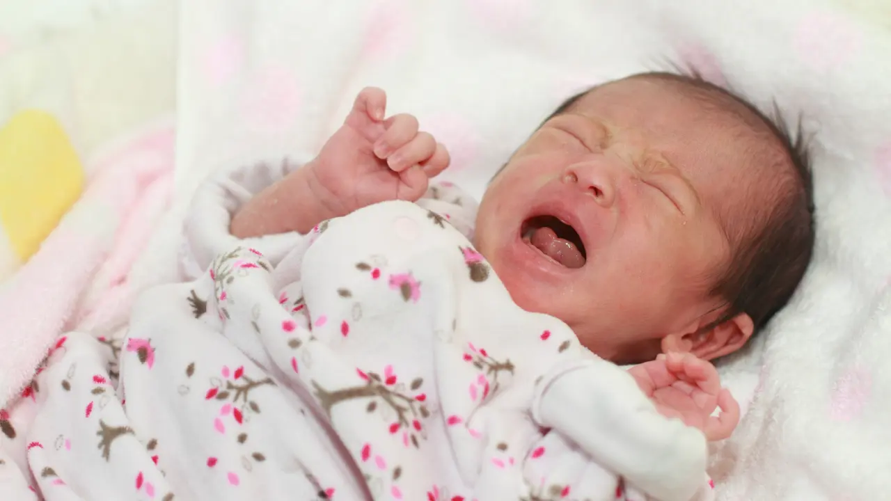 Newborn baby crying, which may be a sign of lip tie or tongue tie affecting feeding