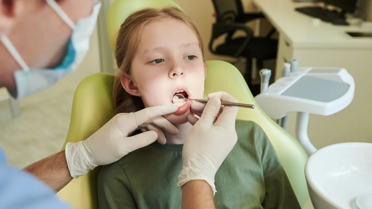 Child receiving a dental examination to monitor healthy tooth and jaw development during a pediatric dental growth monitoring visit.