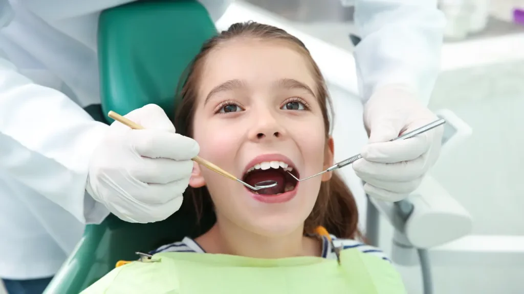 Pediatric dentist performing a routine dental examination to monitor a child's teeth and oral development in Dubai