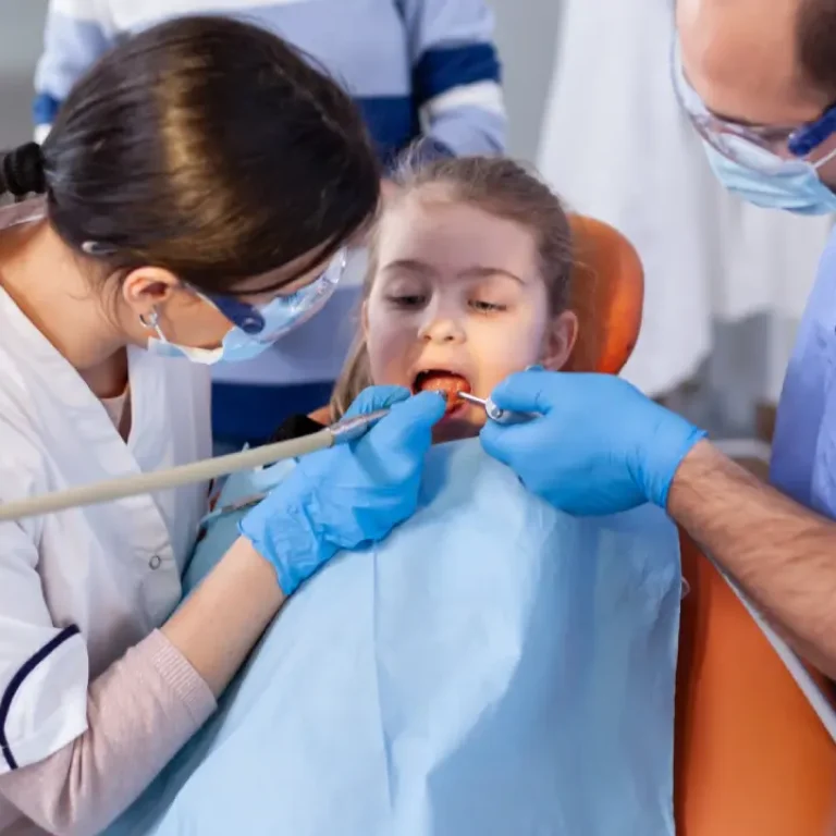 Dentists cleaning young child teeth in clinic chair